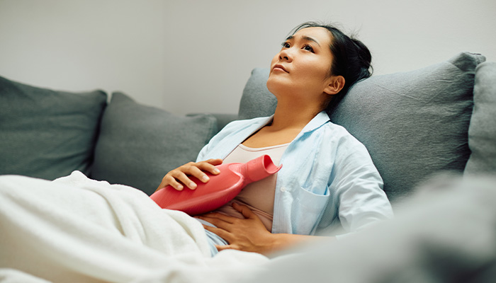 A person holds a hot bottle bottle to their stomach area