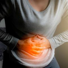 torso of woman holding stomach with both hands in pain
