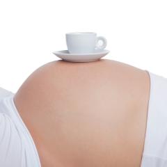 Coffee cup balancing on pregnant stomach