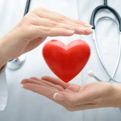 A heart shaped object hovers between the held up hands of a doctor