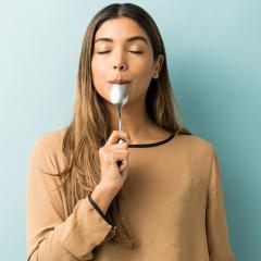 A woman tasting something delicious on a spoon