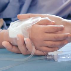 close up of parent holding child's hand in hospital