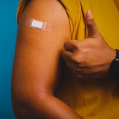 A person giving a thumbs up whilst displaying a bandaged arm.