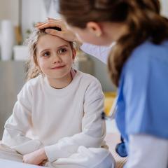 Girl in hospital looked on by sympathetic nurse