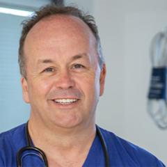 A photograph of Professor John Fraser in scrubs in a hospital setting