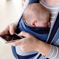 Mother carrying baby while using smartphone