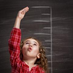 Girl measuring herself - why people grow to different heights. Credit: Shutterstock/Yuganov Konstantin.
