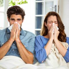 young couple blowing their nose in tissue at home