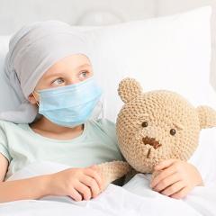 child in hospital bed with teddy