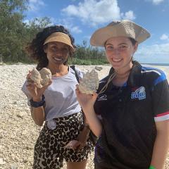 Dr Sonia Shah and Cadence Taylor standing on the beach on Lady Musgrave Island holding shells